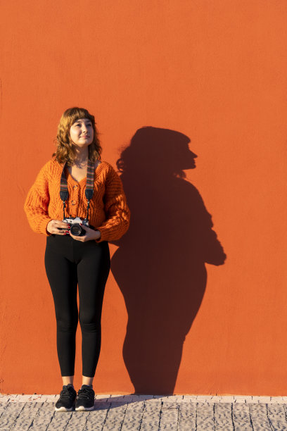 一个女人走过一堵橙色的墙图片下载