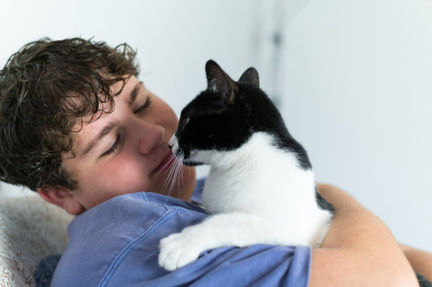 一个十几岁的男孩抱着并亲吻她的猫。一只猫和它主人的照片图片下载