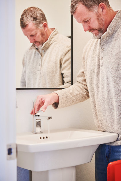 男性房屋检验员在检查住宅物业期间检查浴室水槽的水流图片下载