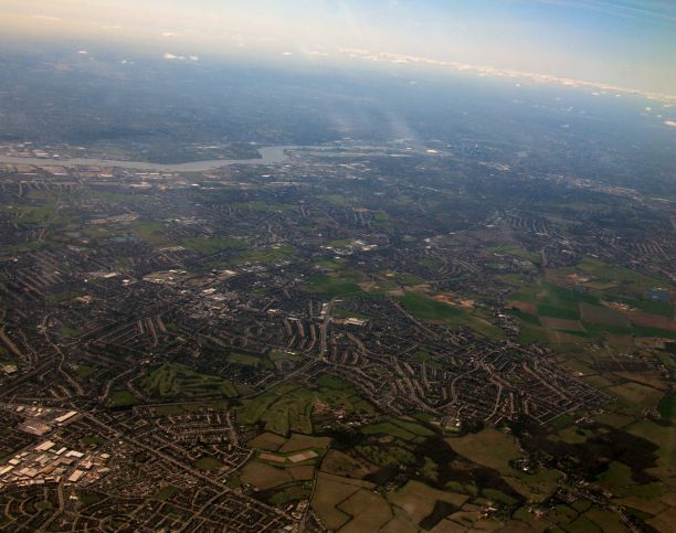 从飞机的角度拍摄白天的绿色田野、建筑和道路图片下载