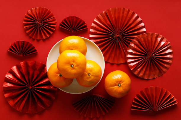 中国新年的节日装饰有红色的袋子，橘子和红色的中国折扇在红色的背景。图片下载