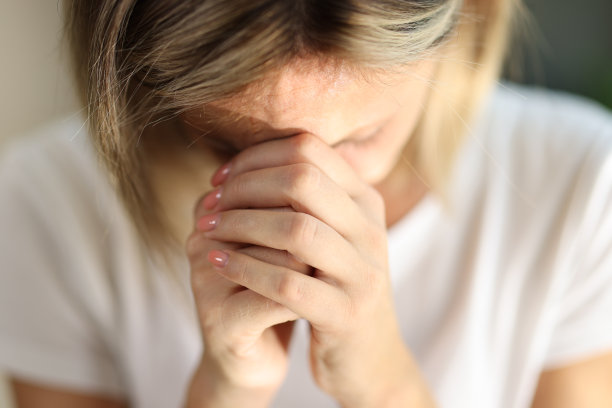 年轻女子双手合十，独自在家祈祷图片下载