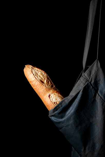 垂直拍摄的美味刚刚烤法棍在一个可重复使用的布袋孤立在黑色背景图片下载