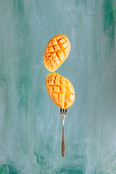 垂直拍摄的芒果与叉子模糊的背景图片下载