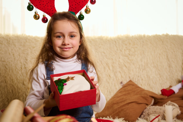 一个白人迷人的小女孩打开一个可爱的圣诞礼物的特写肖像。寒假快乐图片下载