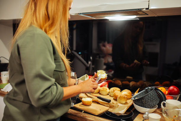 后视图金发无法辨认的女人做饭，在木制厨房角落面包面包上撒黄油。进食障碍图片下载