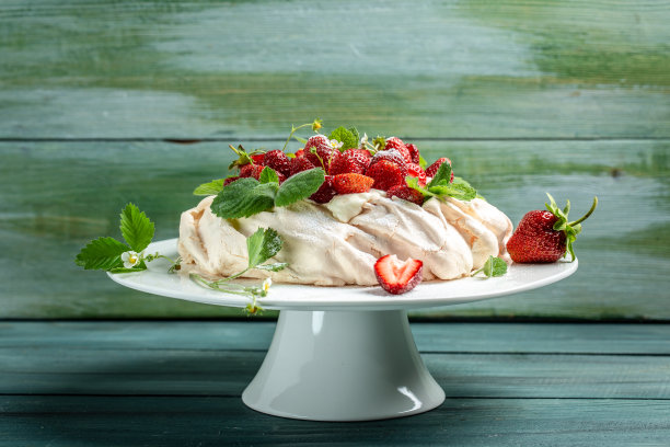 自制美味的蛋白蛋糕巴甫洛娃与鲜奶油，新鲜草莓和薄荷在木制背景，文字的地方，俯视图图片下载