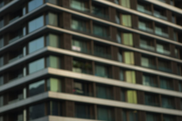 夜晚模糊现代都市公寓楼外观。图片下载