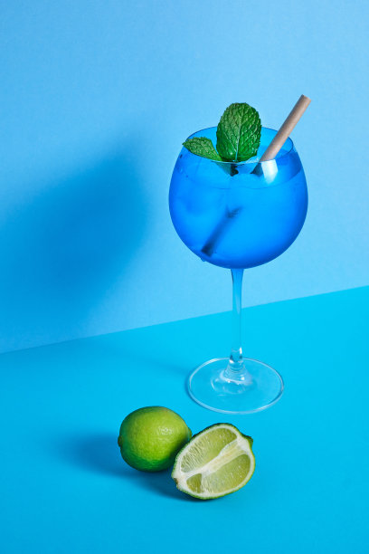 蓝色鸡尾酒杯，在蓝色简约的背景上搭配青柠和薄荷图片下载