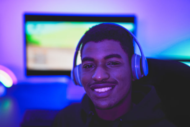 年轻的非洲男孩微笑在相机与电脑的背景-游戏概念图片下载