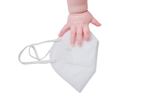 婴儿手和医用口罩n95，特写，隔离在白色背景上。孩子们的手指和白色背景上的一个物体图片下载