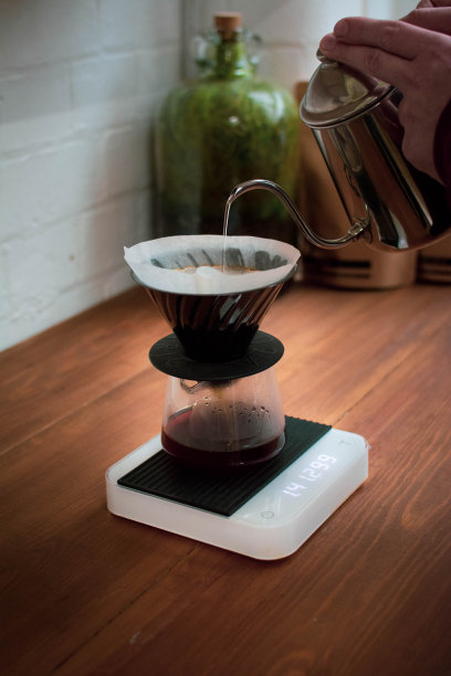 竖版照片：男人将开水倒入手冲咖啡壶图片下载