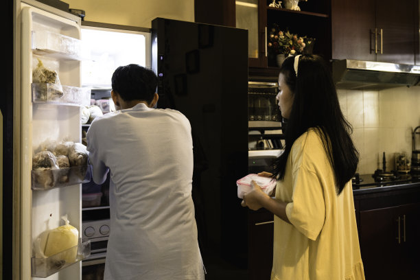 亚洲夫妇聊天，把食品放进冰箱图片下载