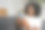 微笑的非洲女人坐在家里的沙发上用智能手机图片下载
