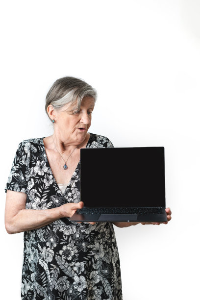 高级灰色头发的女人拿着笔记本电脑惊讶的手势在她的脸上。白色背景图片下载