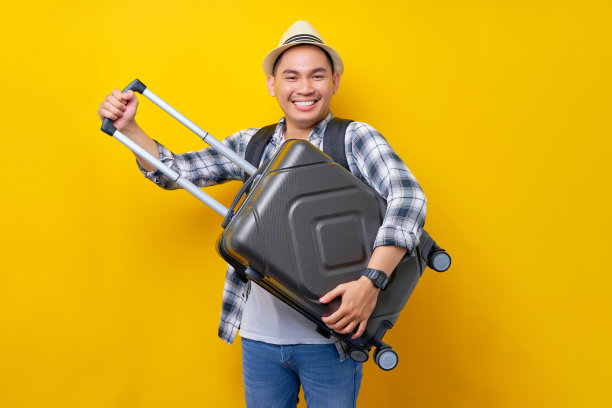 微笑的旅行者游客亚洲男子在休闲服装和帽子背包下的手手提箱包和去移动的黄色背景。周末旅客出行。空中飞行旅程概念图片下载