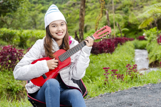 亚洲女子弹吉他享受营地活动图片下载