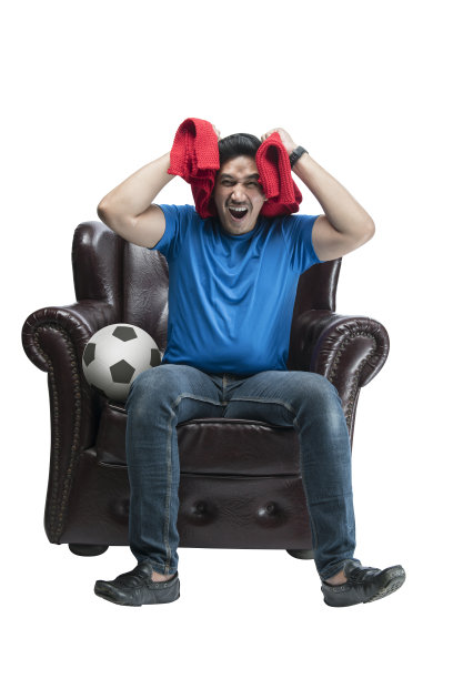 一个带着围巾和球的亚洲男人带着失望的表情坐在沙发上图片下载