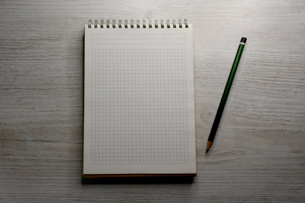 螺旋笔记本和一支笔在木桌上图片下载