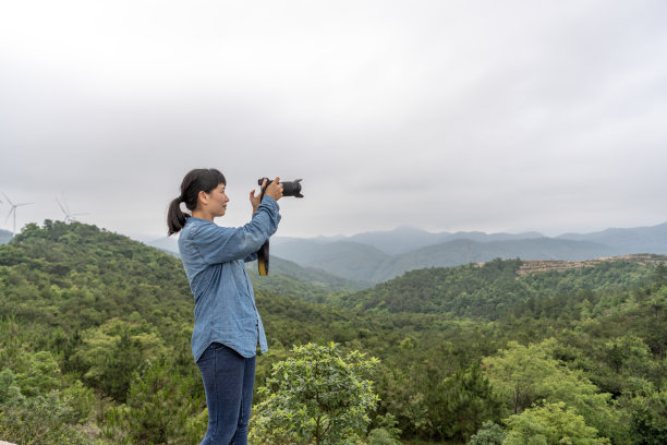 一位女摄影师在野外用相机拍照图片下载