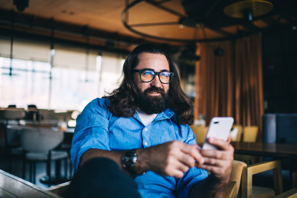 微笑的男性在创意咖啡馆冲浪手机图片下载