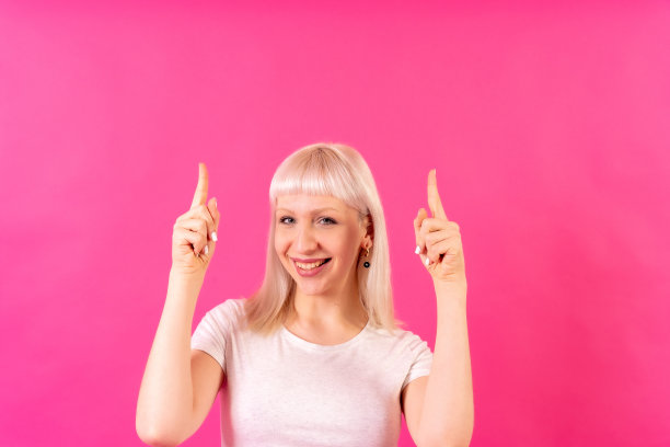 金发白人女孩工作室拍摄的粉红色背景，复制空间，微笑指向图片下载