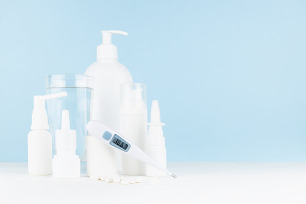 药房白色塑料瓶，喷雾剂，药膏模型与36、6温度计，一杯水，药片放在白色桌子，蓝色墙壁，复制空间。预防和矫正疾病的医学、治疗偏方。图片下载