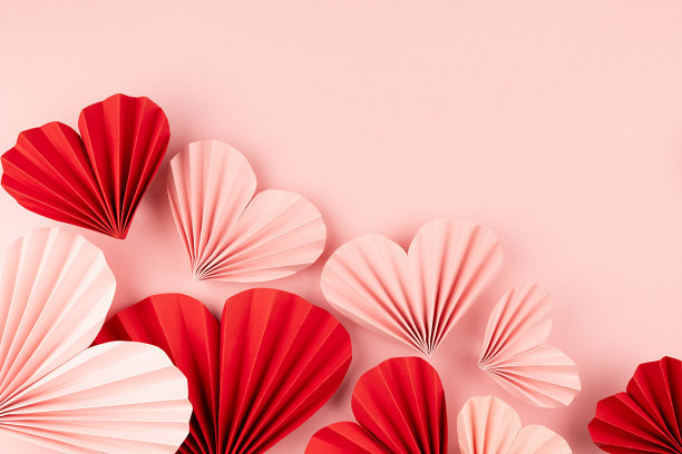 优雅的情人节背景混合甜美的粉红色和红色折纸心形飞行在柔和的淡粉色颜色，页脚边界，复制空间，俯视图，特写。图片下载