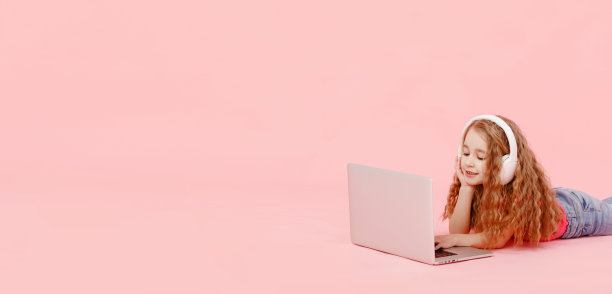 可爱的女孩横幅坐在笔记本电脑旁边的麻绳。孩子们戴着白色耳机伸展身体，做作业或者看动画片，听音乐图片下载