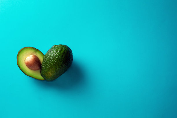 蓝色背景上有新鲜的牛油果。带有文本自由空间的横幅。健康饮食。图片下载