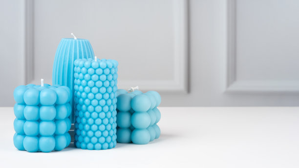 手工制作的橄榄蜡形状各异的蓝色蜡烛，放在家里白色的桌子上。可持续性素食蜡烛，天然材料。简约、现代的照片。副本的空间。水平的旗帜图片下载