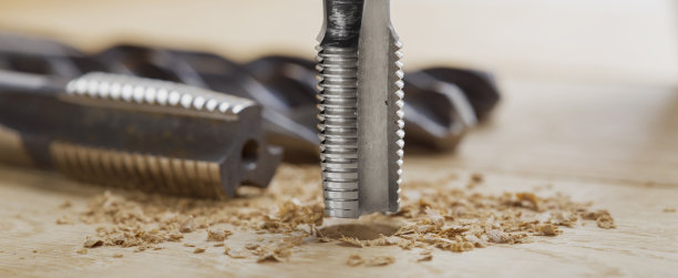 螺纹丝锥在木板上钻切孔。工作机。图片下载