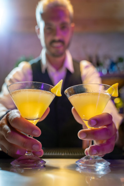 酒吧招待员在夜总会的吧台上供应两种鸡尾酒。图片下载