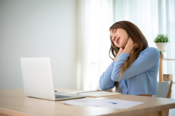 办公室综合症的概念。年轻的亚洲女性在长时间使用笔记本电脑后感到脖子和肩膀疼痛。她伸伸懒腰放松肌肉图片下载