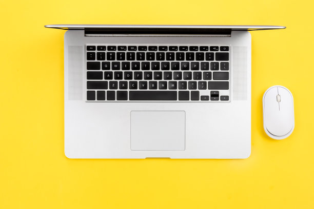笔记本电脑和鼠标在黄色背景上，平铺。图片下载