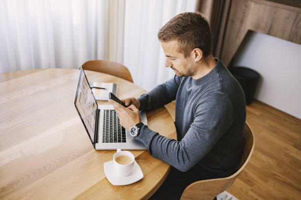 一个大忙人坐在家里用电话打信息。图片下载