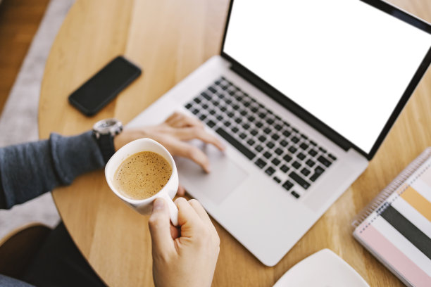 俯视图，一个男人拿着一杯新鲜的咖啡，在家里的键盘上打字。图片下载