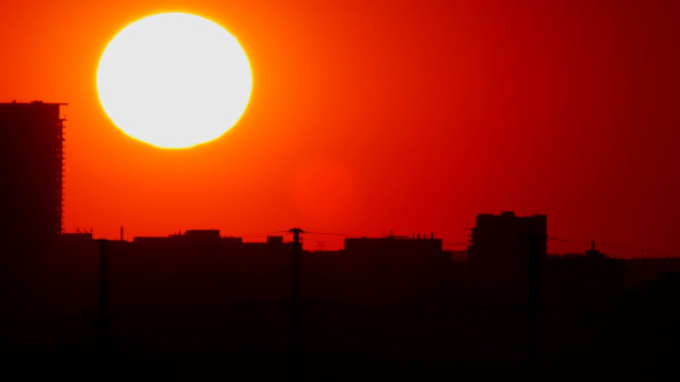 美国市中心的日落，太阳在建筑物的剪影。史诗般的大热红橙色太阳落在城市摩天大楼的轮廓和天际线。图片下载