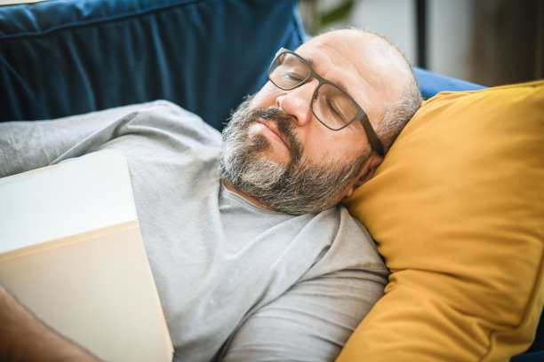 一个男人在房间里的蓝色沙发上休息图片下载