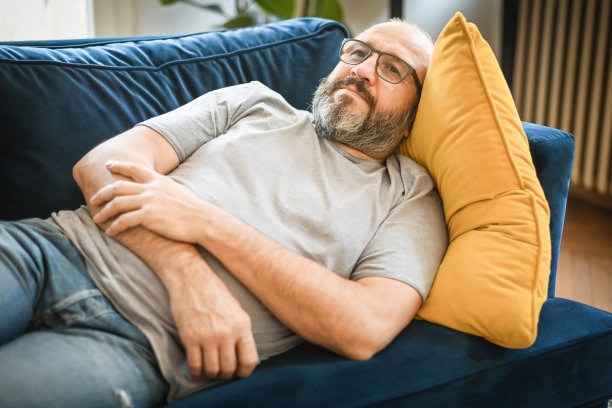 一个男人在房间里的蓝色沙发上休息图片下载