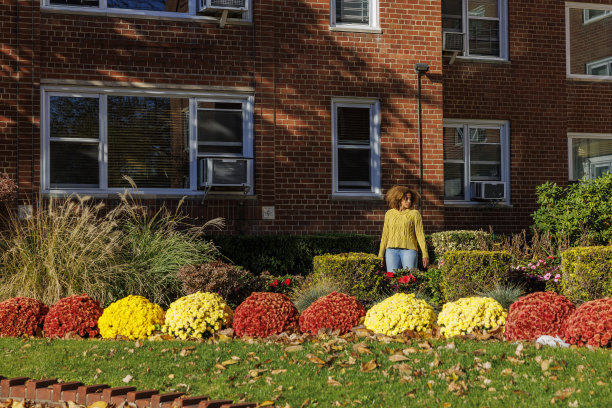 秋日阳光明媚，一名非洲裔多种族妇女走在纽约皇后区的人行道上。图片下载