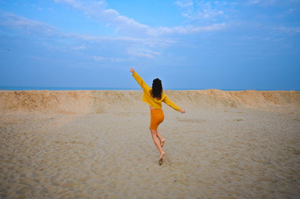 背面肖像的女人在日落的海滩上奔跑图片下载