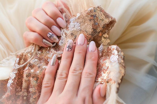 美丽的女性手圣诞指甲设计在金色的背景。指甲设计，有圣诞球图案的美甲。亮片。虫胶，指甲油。图片下载