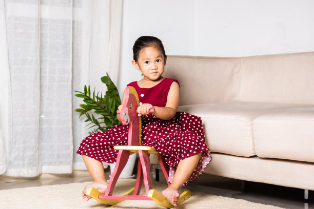 亚洲可爱的小女孩摇摆骑玩具马图片下载