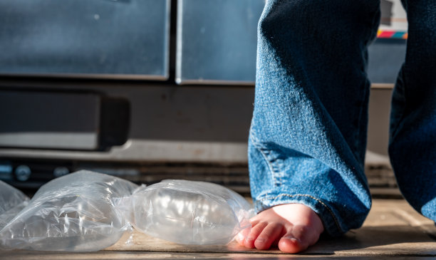 聚焦站在已爆破气泡膜上的儿童的脚图片下载