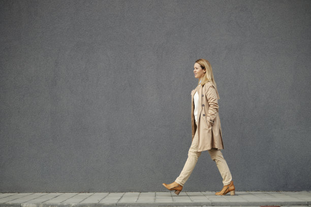 一个穿着漂亮便服的女人走在街上。她穿的是秋装。图片下载