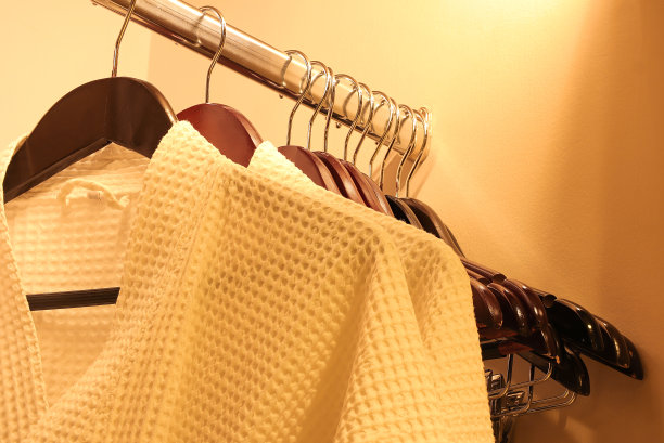 近距离的白色浴袍挂在木制衣柜在豪华酒店。旅行和放松概念图片下载