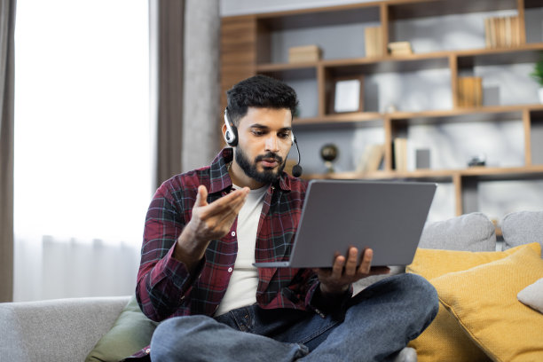 特写年轻的学生男子在无线耳机观看在线课程在笔记本电脑图片下载