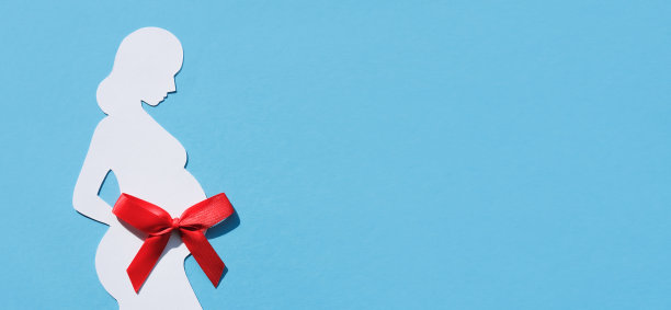 一个孕妇的剪影与红色蝴蝶结在她的肚子上的蓝色背景。横幅，平铺，文字的地方。健康母亲的概念。图片下载