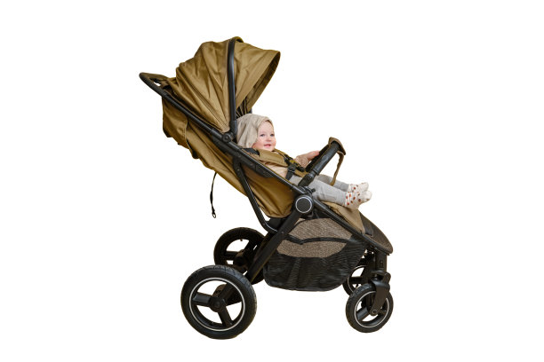 一个快乐的孩子坐在工作室的婴儿车里，孤立在白色背景上。微笑的蹒跚学步的男婴在一个变压器婴儿车运送儿童，年龄八个月图片下载